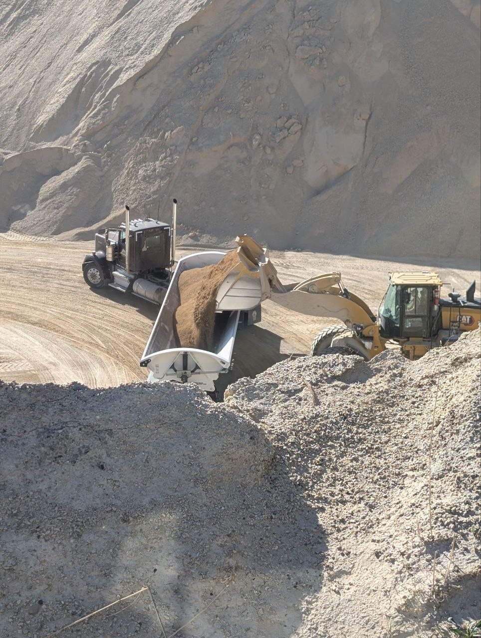 Yellowish/tan crusher fines being loaded into a dump trailer for a Utah delivery